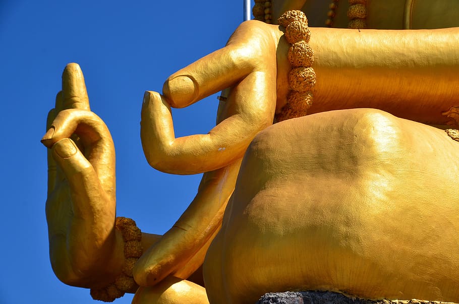 Photo d'une statue dorée où lon zoom sur les mains de ce Buddha